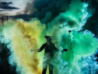 Fototapeta premium Devil with scary mask surrounded by coloured smoke