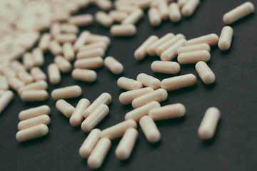 White capsules pills with powder. On black background. 