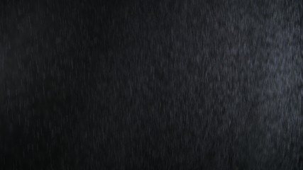 4k Heavy angled rain falling in front of the camera against black screen. Raindrops splashing. Rain closeup vfx insert. Practical seamlessly loopable footage. Heavy rainstorm hitting black surface.