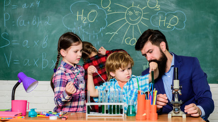 students doing science experiments with microscope in lab. school kids scientist studying science. happy children & teacher. back to school. Little kids learning chemistry in school laboratory