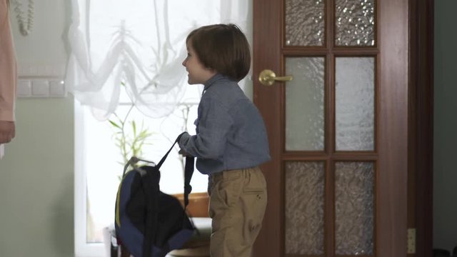 Pretty teenage girl and little brother with backpack entering the house. Children are happy to back home, boy is smiling. Kids as adults