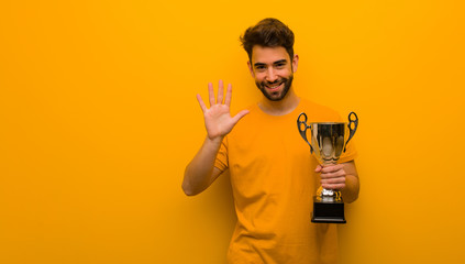Young man holding a trophy showing number five