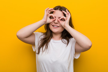 Young curvy plus size woman showing okay sign over eyes