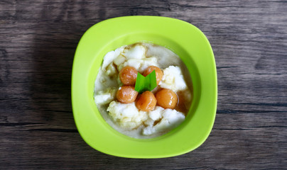 Bubur sum sum on wood background. Bubur sum sum is an Indonesian dessert made by cooking rice flour in coconut milk and served with palm sugar syrup.