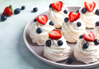 Mini Pavlova meringue with whipped cream and berries.