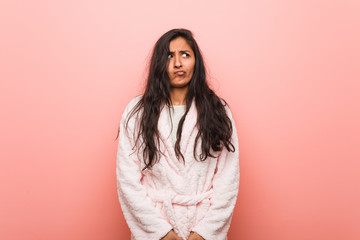 Fototapeta premium Young indian woman wearing pajama confused, feels doubtful and unsure.