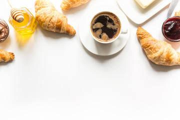 French freshly baked croissants and cup of coffee on white . Space for text.