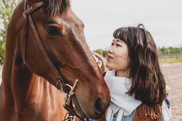 cute chinese cowgirl while taking care of her horse