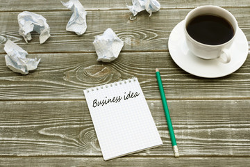 Business ideas, notebook, crumpled sheets of paper, pencil, Cup of coffee on a wooden background.