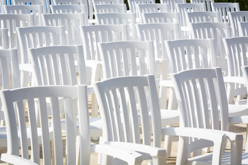 White loose chairs with backrest in summer theater for watching performances on stage.