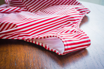 Fototapeta premium Female swimsuit in red strip for bathing on wooden table.
