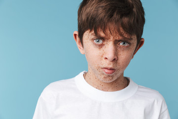 Fototapeta premium Portrait closeup of european teen boy 10-12y with freckles wearing white casual t-shirt looking at camera