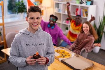 Handsome happy teenager holding little birthday muffin