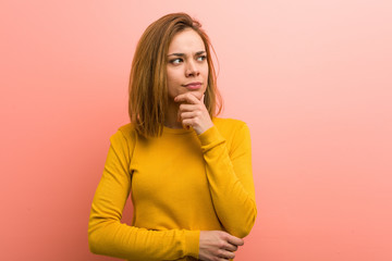 Young pretty young woman looking sideways with doubtful and skeptical expression.