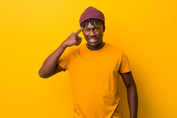 Young black man wearing rastas over yellow background showing a disappointment gesture with...