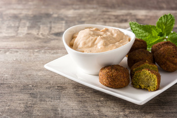 Falafel on a plate and tahini sauce on wooden table. Copyspace