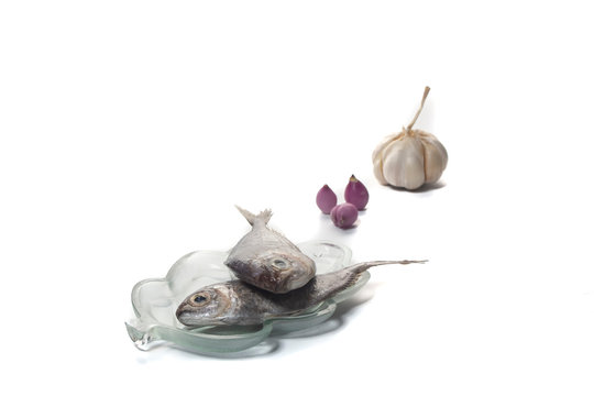 Two fish on a plate with garlic and shallots