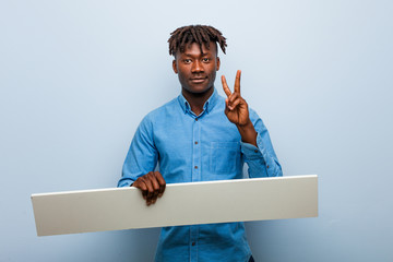 Young rasta black man holding a placard showing number two with fingers.