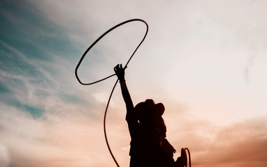 pretty Chinese cowgirl throwing the lasso in a horse paddock - obrazy, fototapety, plakaty