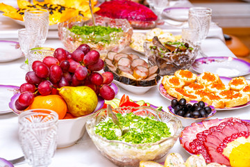 Fototapeta na wymiar Snacks, fruits, sandwiches, salads, caviar and slicing on the holiday table