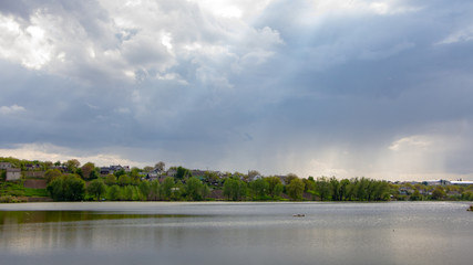 Rain over a small lake, with a farmland royal field