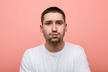 Young casual man blows cheeks, has tired expression. Facial expression concept.