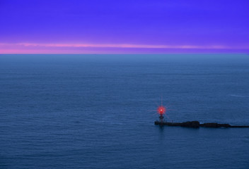 red luminous signal for navigation, entrance to the harbor at sunset