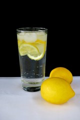 sparkling water with lemon in a transparent glass on a black background