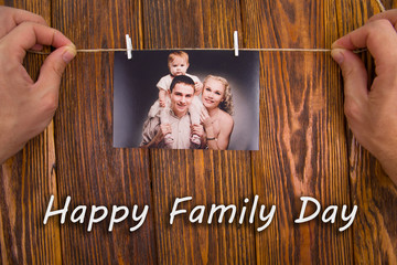 Family day concept. Photo of a young family on a wooden background with an inscription, Happy family day
