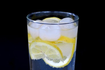 sparkling water with lemon in a transparent glass on a black background