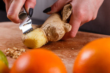 young woman in a gray apron peeling a ginger root