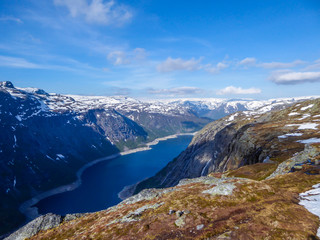 Fototapeta na wymiar A panoramic view from above on a fjord-like Ringedalsvatnet lake, Norway . Snow-capped mountains. Spring slowly coming to the higher parts of the mountains. Water of the lake has a navy blue shade.