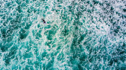 Surfers waiting for a good wave on sunny day. Muriwai Beach, Auckland, New Zealand