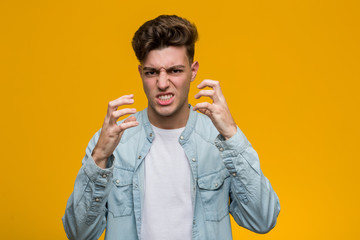 Young handsome student wearing a denim shirt upset screaming with tense hands.