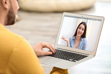 Young man using video chat on laptop at home, closeup. Space for design