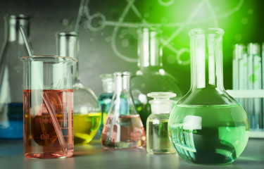 Laboratory glassware on table near chalkboard. Chemistry concept