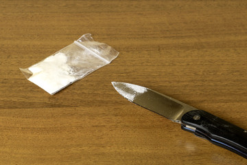 Transparent bag of cocaine and a knife on the table