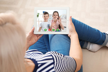 Closeup view of senior woman talking with grandchildren via video chat at home