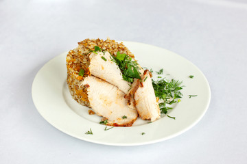 Chicken breast, buckwheat salad with greens on a white plate.