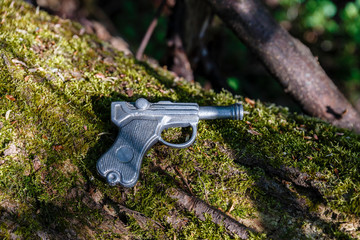 toy gun made of lead lies on an old tree with moss.