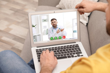 Young man using video chat on laptop in living room, closeup. Space for design