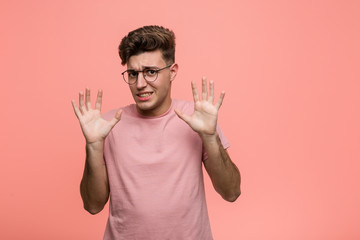 Young cool caucasian man rejecting someone showing a gesture of disgust.