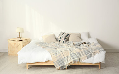 Fototapeta na wymiar Bed with pillows and plaid in modern room interior