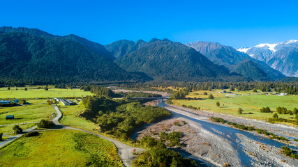 Obraz premium River running through sunny valley with high mountains on the background. West Coast, South Island, New Zealand