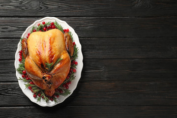 Platter of cooked turkey with garnish on wooden background, top view. Space for text