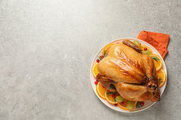 Platter of cooked turkey with garnish on grey background, top view. Space for text