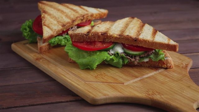 man places club sandwich with grilled bread lettuce tomato cucumber tuna sauce on cutting board healthy breakfast