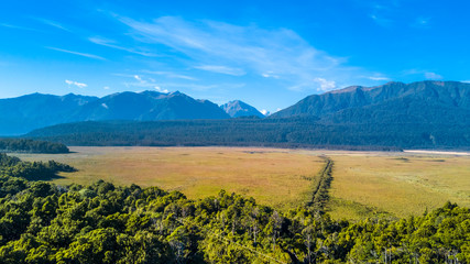 Fototapeta premium Sunny valley at the foot of high mountains. West Coast, South Island, New Zealand