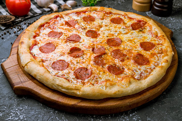 Pepperoni pizza on board on wooden background