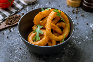Onion rings in batter on black concrete